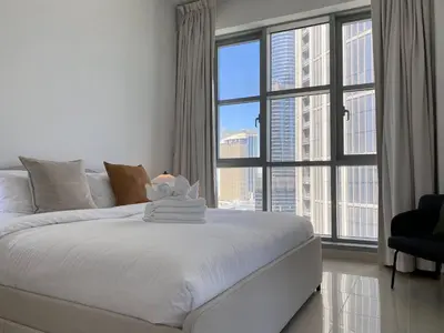 a white bed in a room with a large window at Lux BnB Standpoint Tower Burj & Fountain Views in Dubai