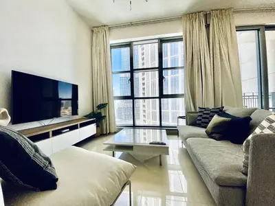 a living room with a couch and a tv and windows at Lux BnB Standpoint Tower Burj & Fountain Views in Dubai