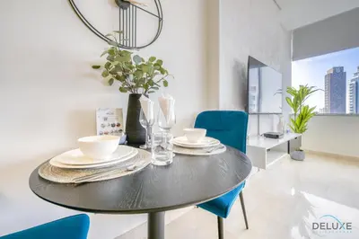 a dining room with a black table and blue chairs at Welcoming Studio at Sky Gardens DIFC By Deluxe Holiday Homes in Dubai