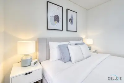 a bedroom with a white bed and two pictures on the wall at Welcoming Studio at Sky Gardens DIFC By Deluxe Holiday Homes in Dubai