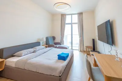 a bedroom with a bed and a table and a television at Luxury Escapes - Cozy Studio In front of Metro Stn - Access to Gym & Pool - Aura Azizi in Dubai