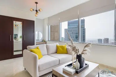 a living room with a white couch and yellow pillows at Sunny Studio at Sky Gardens DIFC by Deluxe Holiday Homes in Dubai