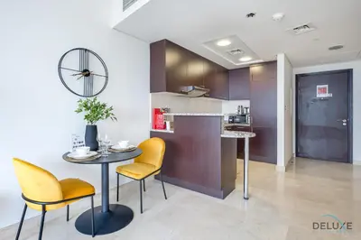 a kitchen with yellow chairs and a table and a counter at Sunny Studio at Sky Gardens DIFC by Deluxe Holiday Homes in Dubai