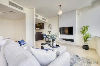 a living room with a white couch and a tv at Best Value Modern 1BR with Pool & Stunning Views by Deluxe Holiday Homes in Dubai