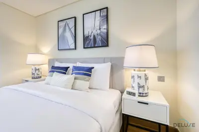 a bedroom with a large white bed with two lamps at Best Value Modern 1BR with Pool & Stunning Views by Deluxe Holiday Homes in Dubai