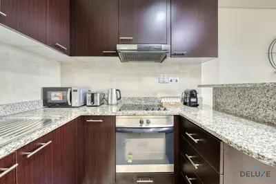 a kitchen with wooden cabinets and a stainless steel oven at Great Deal Cozy 1BR with Pool & City Views by Deluxe Holiday Homes in Dubai