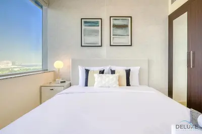 a bedroom with a large white bed and a window at Great Deal Cozy 1BR with Pool & City Views by Deluxe Holiday Homes in Dubai