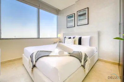 a bedroom with a large white bed with a window at Great Deal Cozy 1BR with Pool & City Views by Deluxe Holiday Homes in Dubai