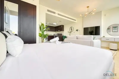 a bedroom with a white bed and a living room at Great Deal Cozy 1BR with Pool & City Views by Deluxe Holiday Homes in Dubai