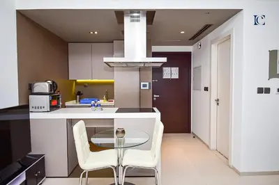 a kitchen with a glass table and white chairs at Luxury Escapes - Modern studio in West Avenue Dubai Marina in Dubai