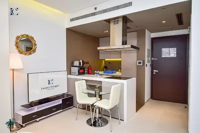 a kitchen with a glass table and white chairs at Luxury Escapes - Modern studio in West Avenue Dubai Marina in Dubai