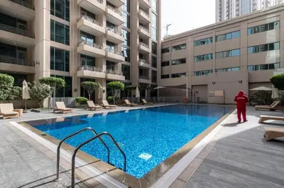a person standing next to a swimming pool in a building at Silkhaus lovely studio with Downtown view in Boulevard central in Dubai