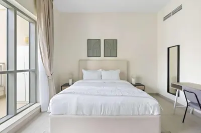 a white bedroom with a bed and a desk at Silkhaus with full Burj Khalifa & fountain view 1BDR in Downtown in Dubai