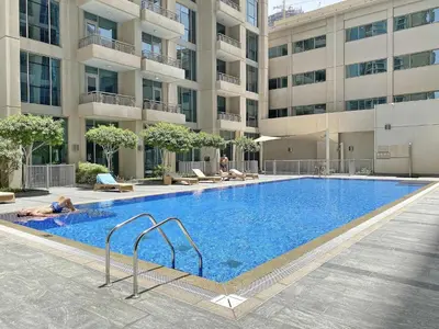 a large swimming pool in front of a building at Silkhaus with full Burj Khalifa & fountain view 1BDR in Downtown in Dubai