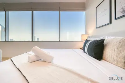 a white bed in a room with large windows at Opulent Studio at Sky Gardens DIFC by Deluxe Holiday Homes in Dubai