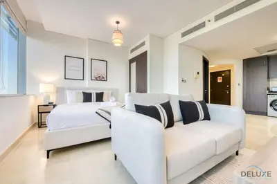 a white bedroom with a bed and a couch at Opulent Studio at Sky Gardens DIFC by Deluxe Holiday Homes in Dubai