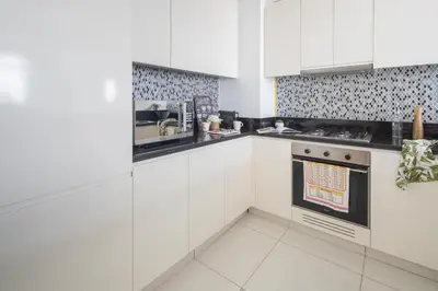 a white kitchen with white cabinets and a stove at Frank Porter - Paramount Midtown in Dubai