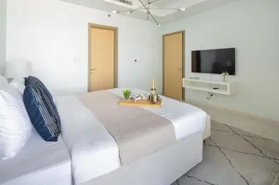 a white bedroom with a bed and a tv at Frank Porter - Paramount Midtown in Dubai