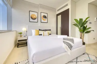 a bedroom with a large white bed and a plant at Refreshing Studio at Sky Gardens DIFC by Deluxe Holiday Homes in Dubai