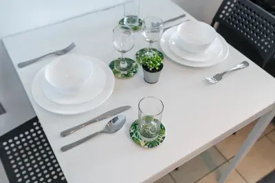a white table with plates and glasses and silverware at White Sage - Luxurious Studio in JLT With City Skyline View in Dubai