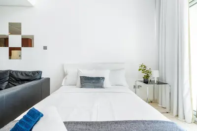 a white bedroom with a large bed and a window at White Sage - Luxurious Studio in JLT With City Skyline View in Dubai