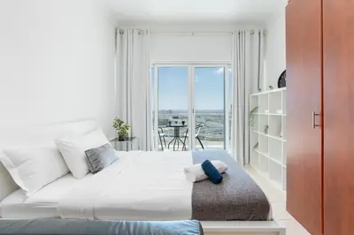 a bedroom with a large white bed with a balcony at White Sage - Luxurious Studio in JLT With City Skyline View in Dubai