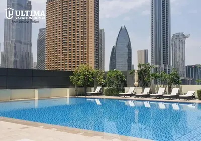a swimming pool with chairs and a city skyline at Elegant Apartment with Direct access to Dubai Mall in Dubai