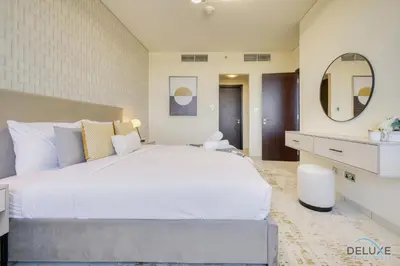 a bedroom with a large white bed and a mirror at Jubilant 1BR at Sky Gardens DIFC by Deluxe Holiday Homes in Dubai