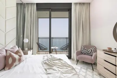 a bedroom with a bed and a chair and a balcony at GuestReady - Luxury l Sea Views Oasis in Dubai