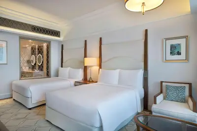 a hotel room with two beds and a chair at Waldorf Astoria Dubai Palm Jumeirah in Dubai