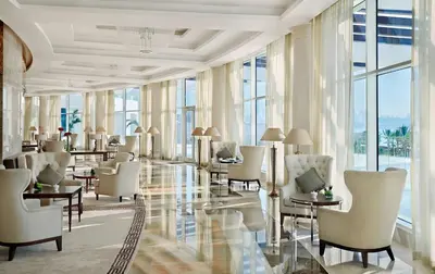 a hotel lobby with white chairs and tables and windows at Waldorf Astoria Dubai Palm Jumeirah in Dubai