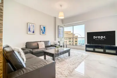 a living room with a couch and a tv at 300m From The Beach - JBR Apartment with Sea & Dubai Eye Views in Dubai