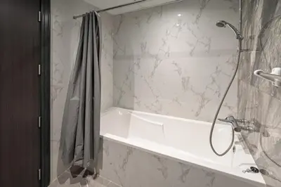 a bathroom with a shower with a white tub at Family-Sized 4BR Pool, Jacuzzi & Gym in Dubai