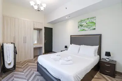 a bedroom with a large bed with white sheets at Spacious 4BR En-Suite Apt I Gym, Pool & Parking in Dubai