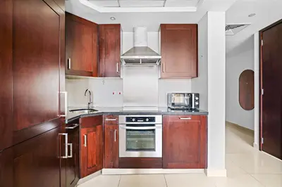 a kitchen with wooden cabinets and a stove top oven at Silkhaus cozy central studio in Downtown in 29 Boulevard in Dubai