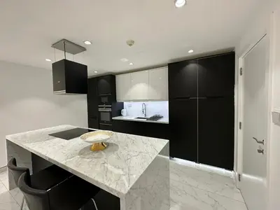 a kitchen with black cabinets and a marble counter top at STYLISH 2 BEDROOM SERVICE APARTMENT with SEA VIEW in Dubai