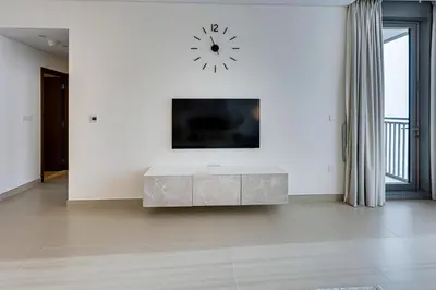 a white living room with a clock on a white wall at Sea View 2BD in new 52 42 tower Dubai Marina in Dubai