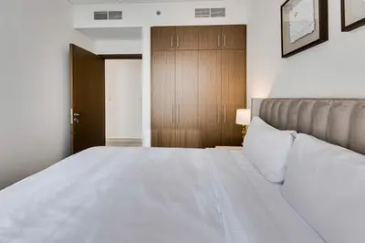 a bedroom with a white bed and a wooden door at Sea View 2BD in new 52 42 tower Dubai Marina in Dubai