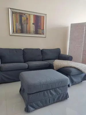 a living room with a blue couch and ottoman at Studio in the heart of Sports City -great view & amenities! in Dubai