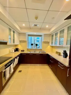 a large kitchen with brown cabinets and a window at 2BR Dubai Burj View Downtown Skyline with Pool, Gym, & Parking in Dubai