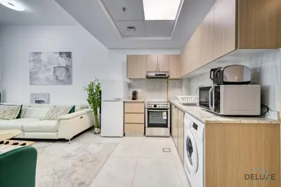 a kitchen and living room with a couch and a microwave at Urban 1BR at Binghatti Stars Dubai Silicon Oasis by Deluxe Holiday Homes in Dubai