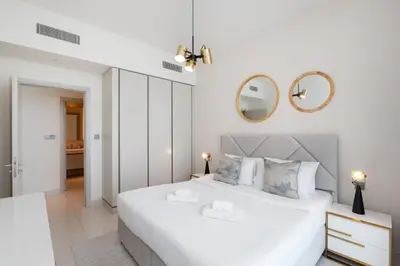 a white bedroom with a large white bed and a mirror at Sunrise Bay, Emaar Beachfront Dubai Harbour - Mint Stay in Dubai