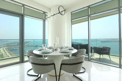 a dining room with a table and chairs and windows at HiGuests - Superlative apt with private beach access in Dubai
