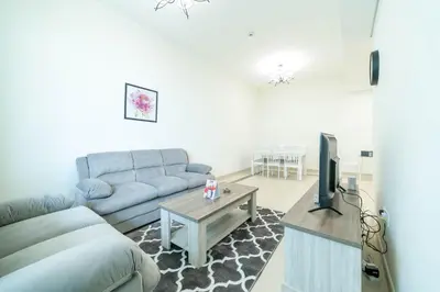 a living room with a couch and a tv at OYO 589 Najma Tower, Two bedrooms Apartments, Sports City in Dubai