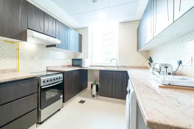 a large kitchen with wooden cabinets and a sink at OYO 589 Najma Tower, Two bedrooms Apartments, Sports City in Dubai