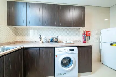 a kitchen with a washing machine and a refrigerator at OYO 589 Najma Tower, Two bedrooms Apartments, Sports City in Dubai