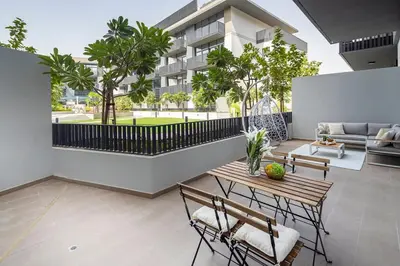 a patio with a wooden table and chairs in front of a building at Frank Porter - Belgravia 3 in Dubai