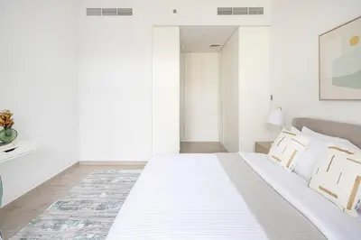 a white bedroom with a large white bed with pillows at Frank Porter - Belgravia 3 in Dubai