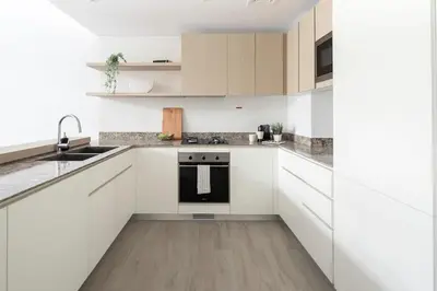 a white kitchen with white cabinets and a sink at Frank Porter - Belgravia 3 in Dubai