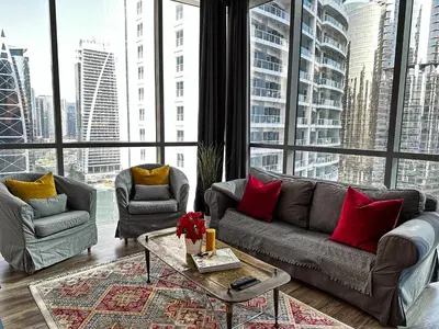 a living room with a couch and two chairs and large windows at La Buena Vida Holiday Homes - Luxe 1BD, boutique apt full lakeview 1m to Metro, Lake & Almas Tower in Dubai